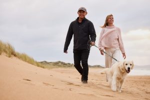 Man, woman and dog walk on beach