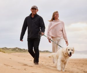 Man, woman and dog walk on beach